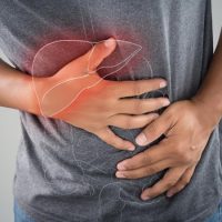 مردی با تیشرت توسی که از شدت درد دستش بر روی شکم و منطقه صفرایش است